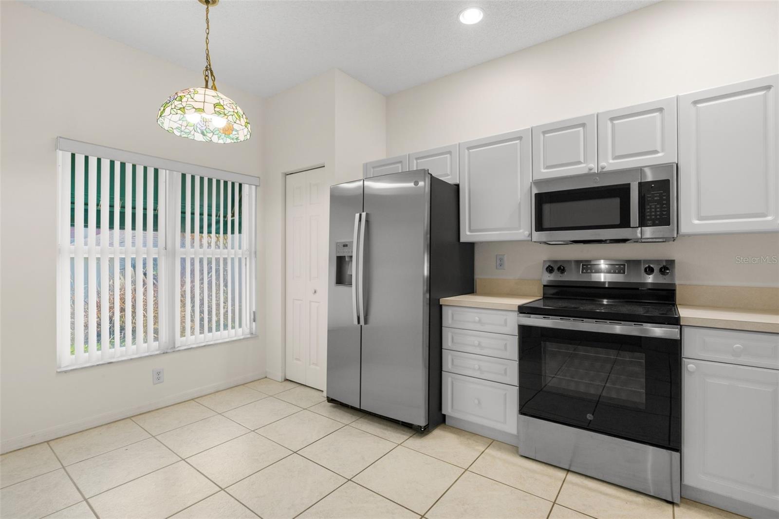 Spacious eat-in kitchen featuring ample cabinetry, generous counter space, and a dedicated dining area beneath a decorative pendant light.