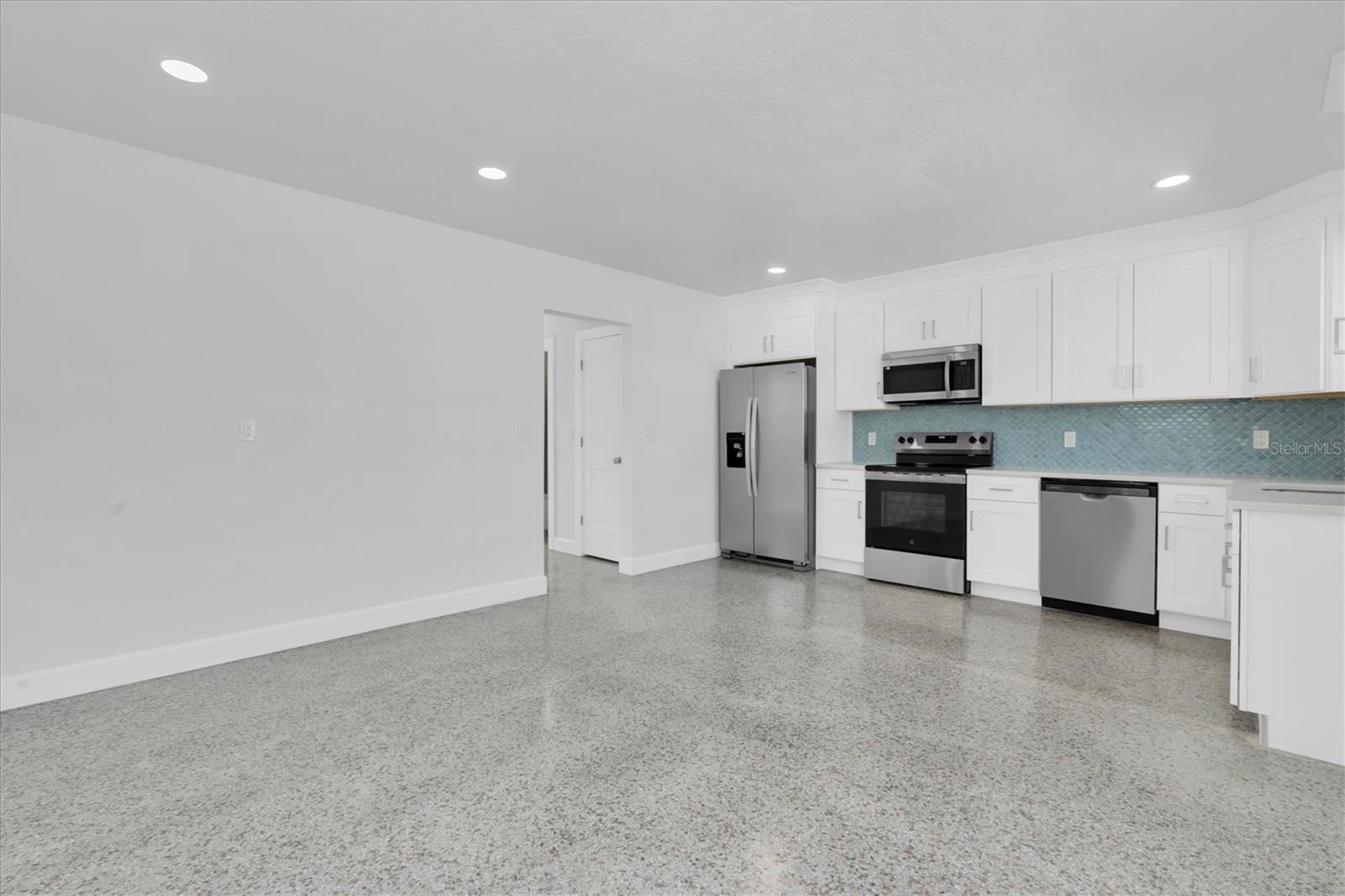 Newly Remodeled Kitchen with Stainless Steel Appliances, Tiled Backsplash, Recessed Lighting, White Cabinets, and Quartz Countertops - Left Side