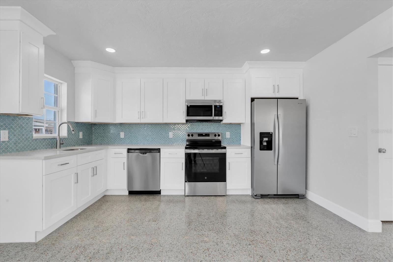 Newly Remodeled Kitchen with Stainless Steel Appliances, Tiled Backsplash, Recessed Lighting, White Cabinets, and Quartz Countertops - Right Side