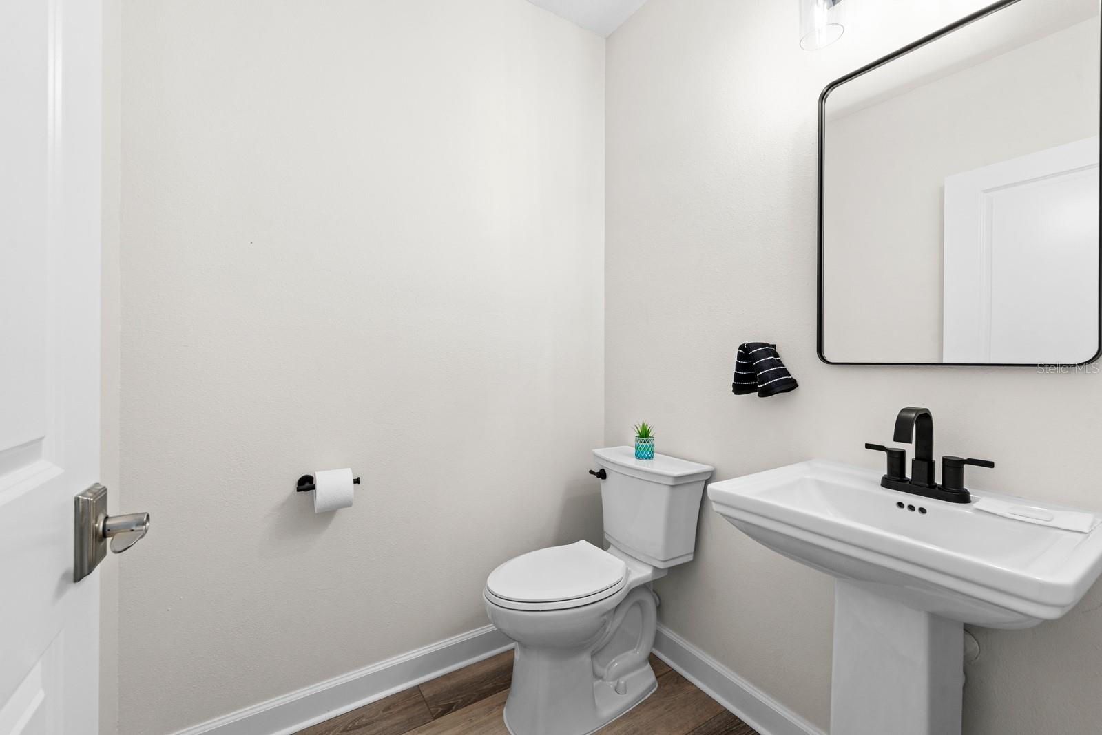 The half bathroom downstairs has a new Toilet, Pedestal Sink, Lighting, Mirror, and all new, updated hardware.