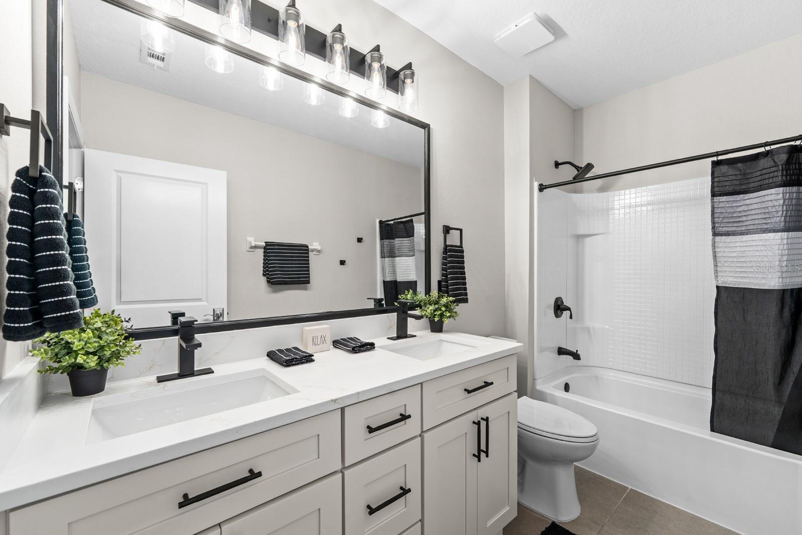 The secondary bathroom upstairs features a new double-sink vanity with modern faucets, a new mirror, new lighting, new hardware in the shower, a new toilet, and it's all so esthetically pleasing!