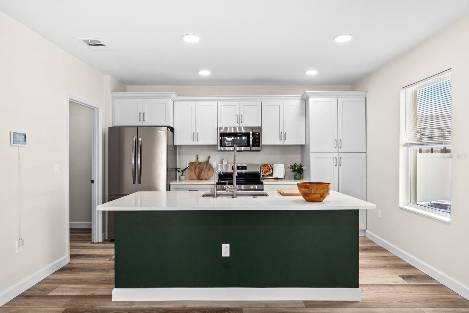 The kitchen has all new cabinets with the soft-close feature, the tall cabinet on the right replaced smaller cabinets.  Quartz countertops, new stainless appliances, new and updated sink and faucet, and the walk-in pantry to the left has new custom shelving.