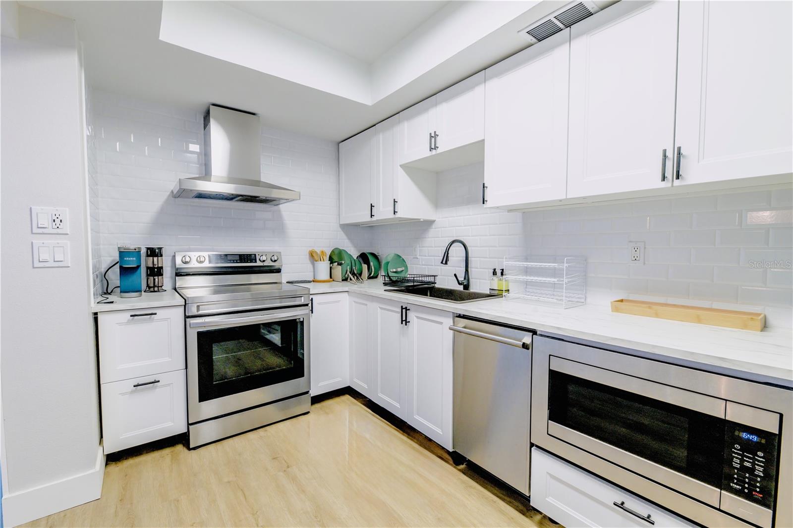 Kitchen with Tray Ceilings and Stainless Steel Appliances: Stove, Hood, Dishwasher, Microwave