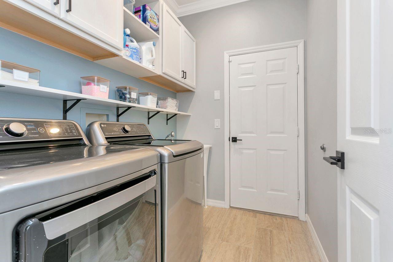 Inside Laundry Room with extended Utility Sink, Custom Cabinets, and Shelving and access to Garage