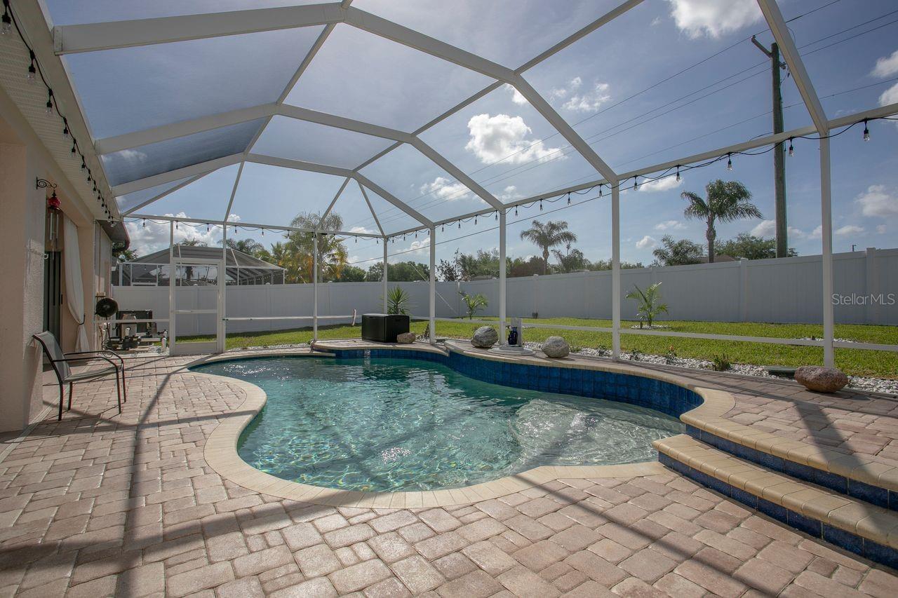 Heated Pool and Pool Cage with Pavered Deck, View to Beautiful Backyard and Landscaping
