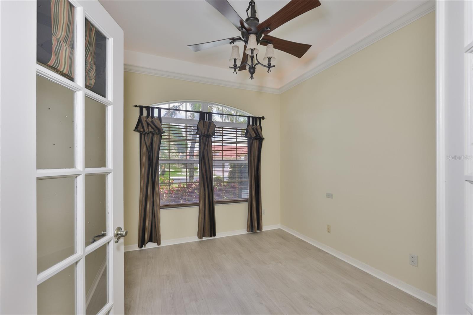 The den is spacious and bright with matching light fixtures, glass paneled French doors and a lighted ledge near the ceiling for ambiance.