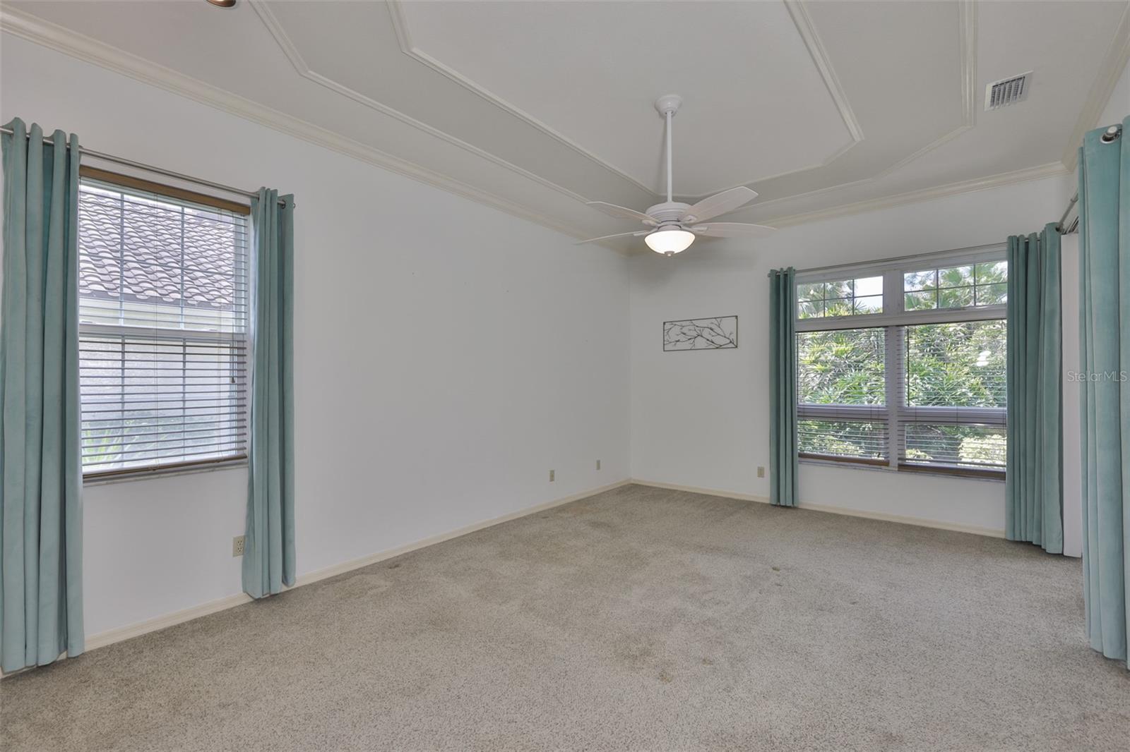 The primary bedroom is spacious and bright with custom ceiling details to enhance the room.