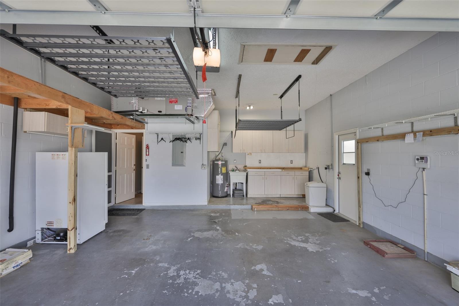 The OVERSIZED garage has a work space, multiple overhead shelving and a freezer that conveys!
