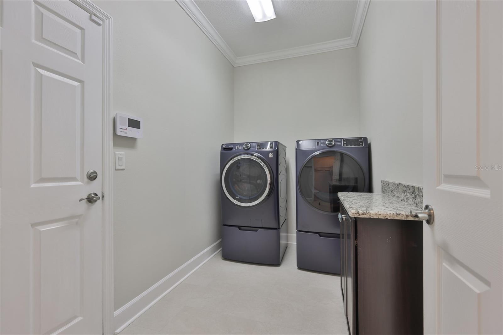Laundry room is spacious with the washer and dryer setup on pedestals.