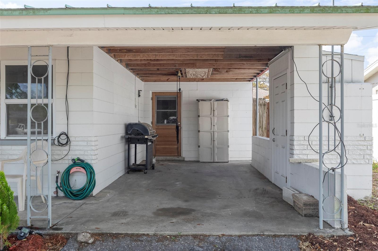 Carport with overhead storage and large cabinet on the right