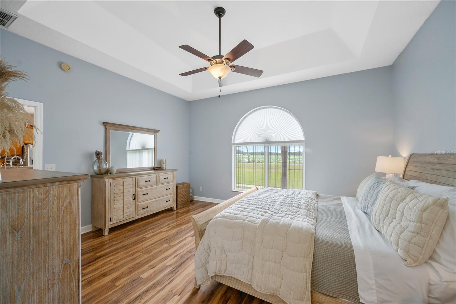 The generously sized primary suite serves as a private retreat offering sweeping views of the front yard and features a striking tray ceiling that creates a bright, light, and airy feel.