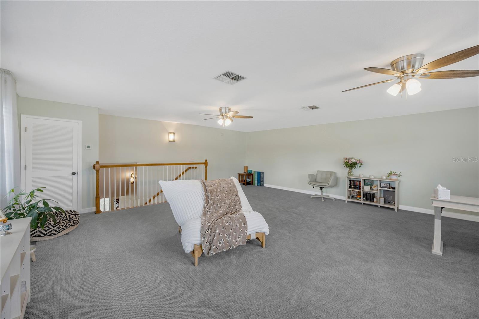 Upstairs loft/bonus room has Berber carpet, a small storage closet and 2 ceiling fans.