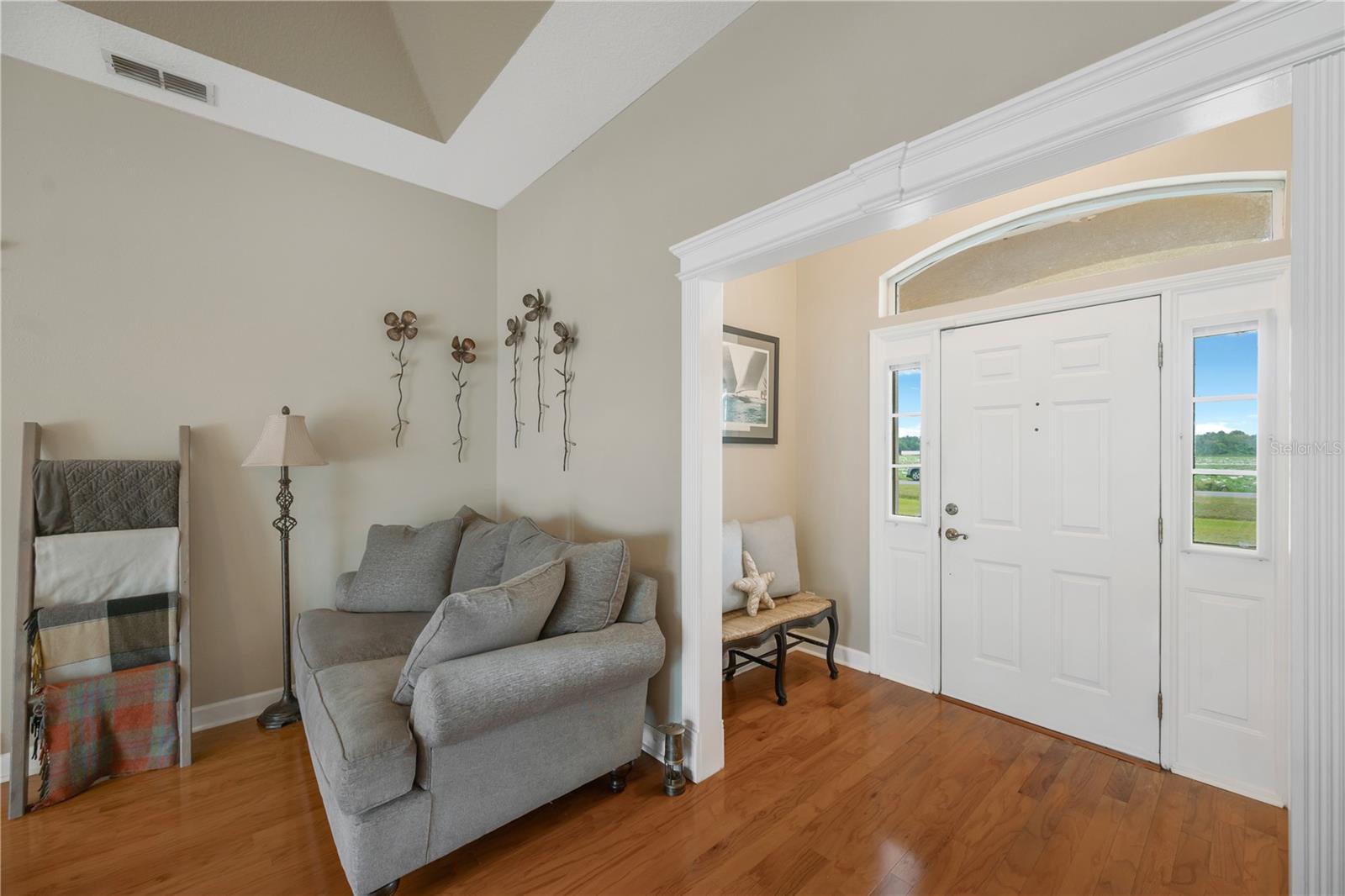 A welcoming front door with sidelights and an elegant arched transom opens into a bright foyer, where a convenient coat closet is neatly tucked out of sight.