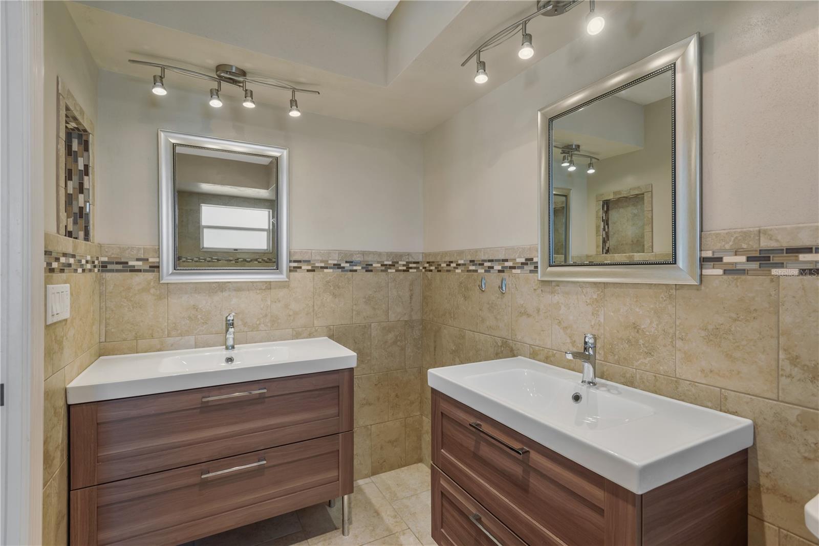 Regal Master bath with His/Hers vanities, beautiful neutral tile, listello accent and upscale lighting.