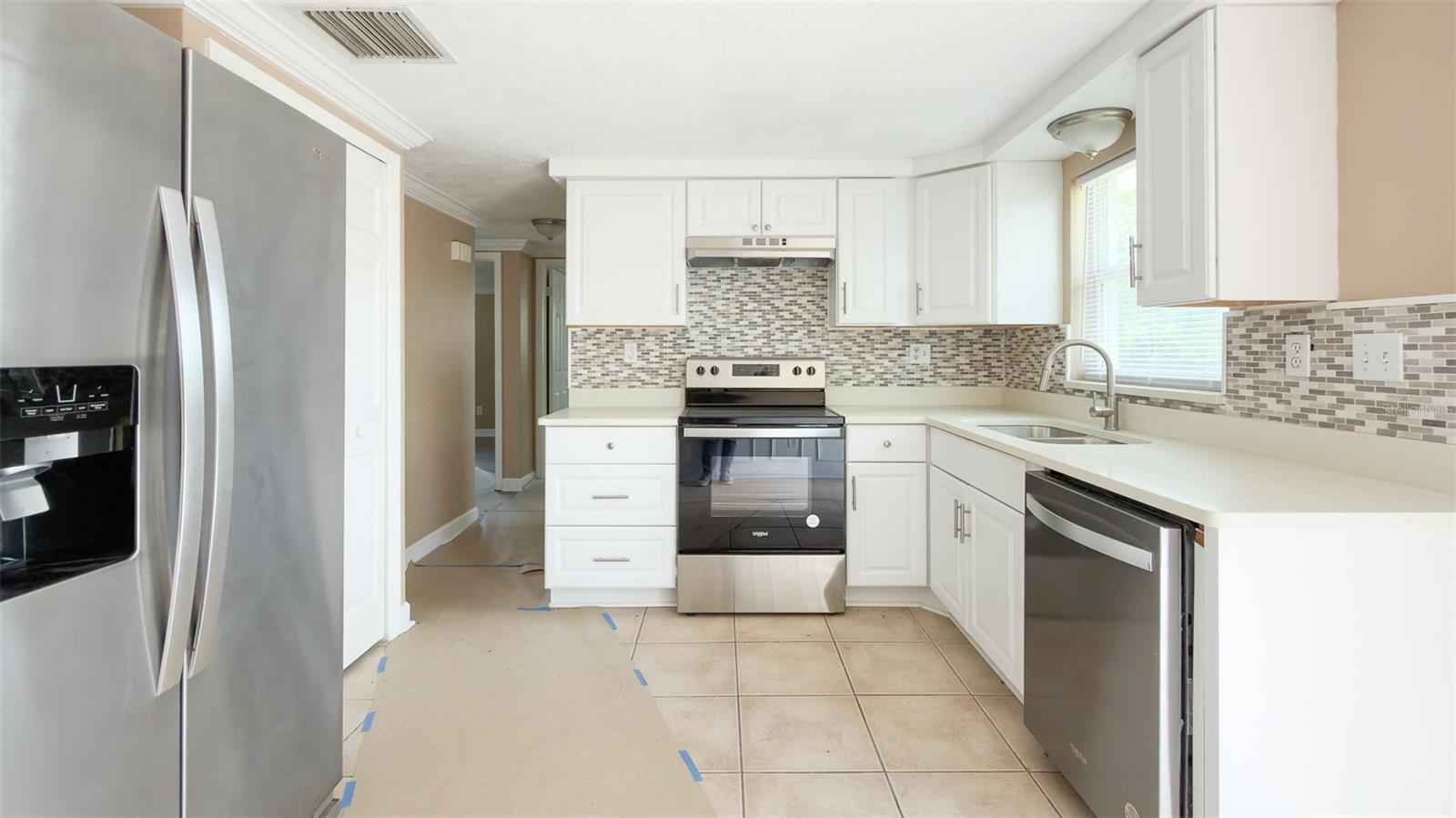 Fully renovated kitchen with white cabinetry and modern quartz countertops.