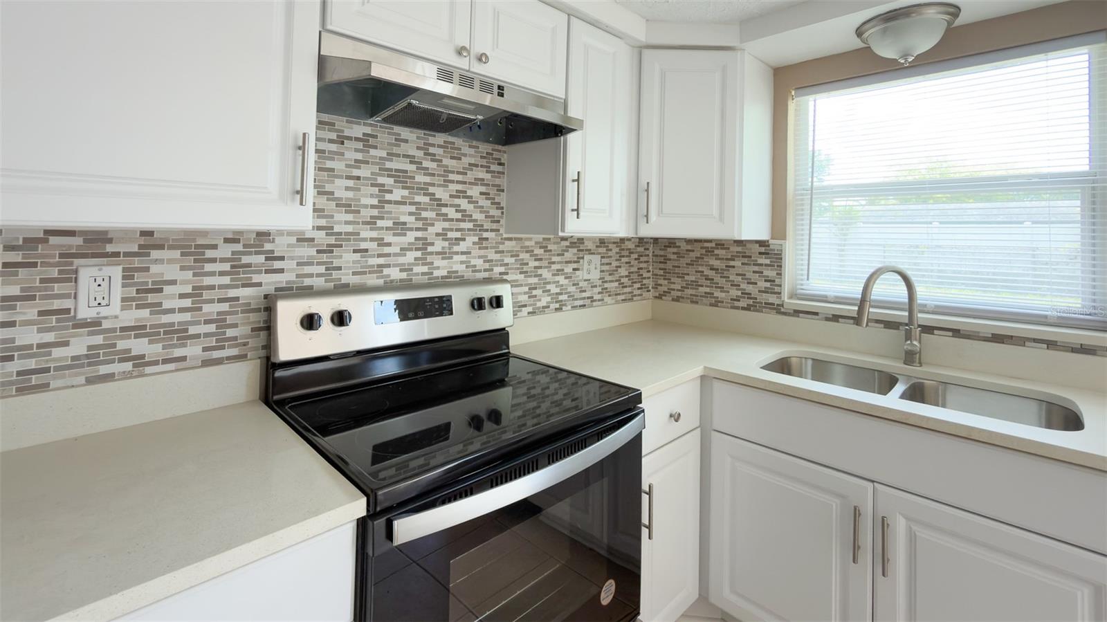 Stylish kitchen featuring stainless steel appliances and custom tile backsplash.