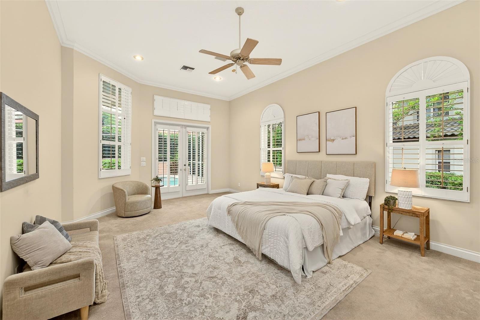 Primary bedroom with french doors to the pool area.