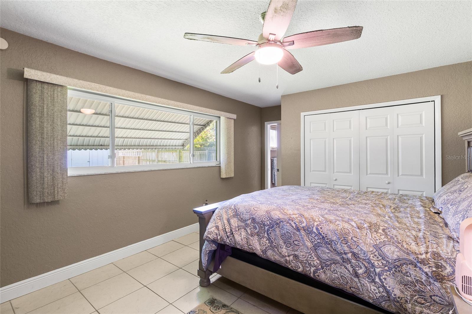 Primary Bedroom with tile floors, ceiling fan, window treatments, dual closets and it's own bath