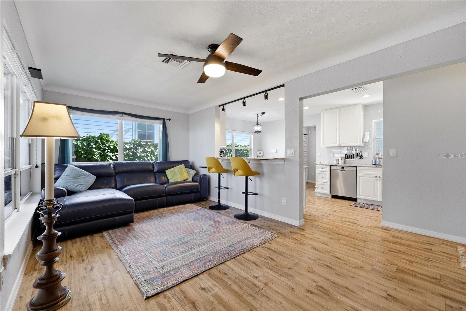 Open concept living space flowing into kitchen with breakfast bar seating