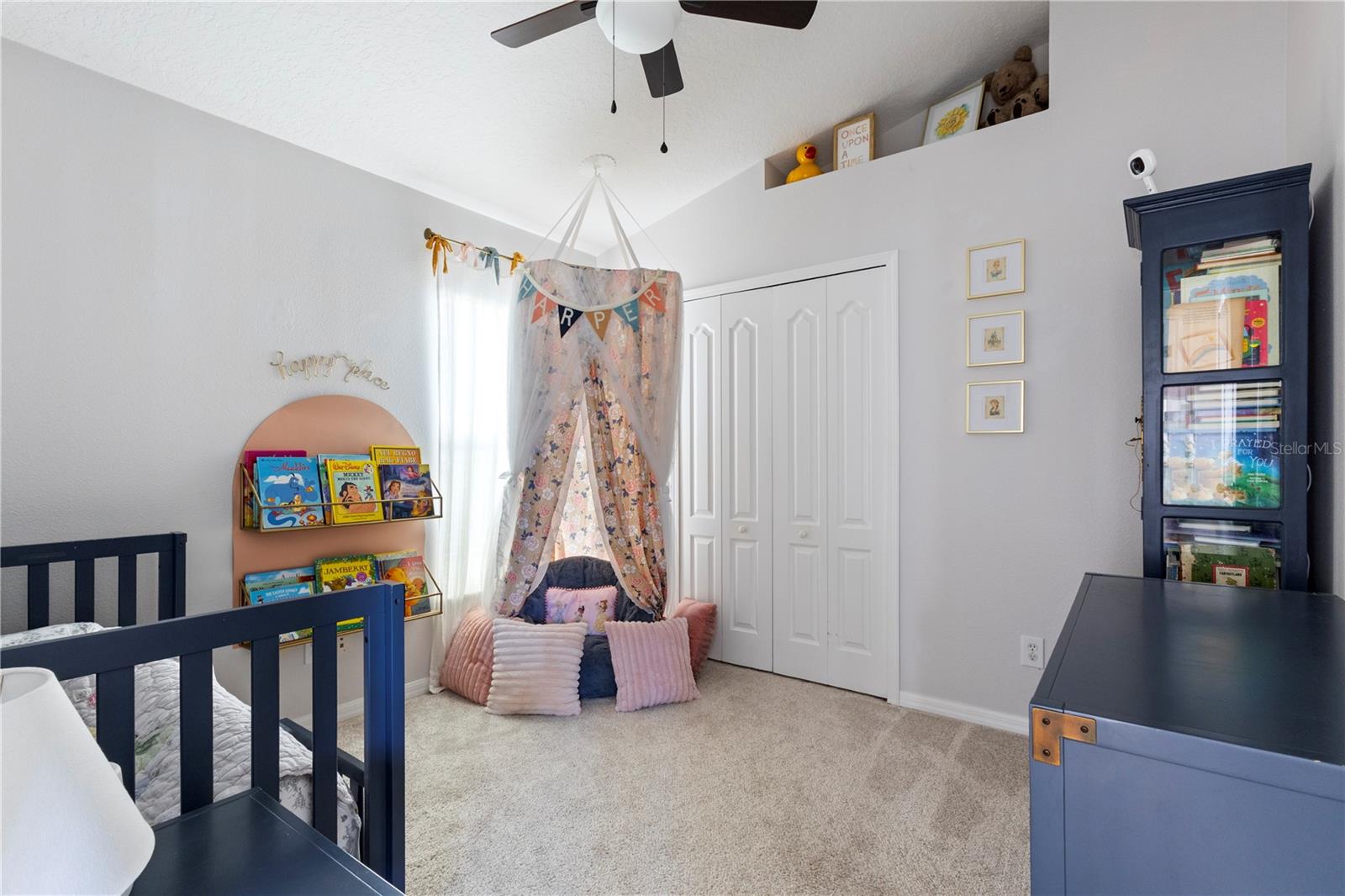 Whimsical children's bedroom featuring a charming built-in reading nook with arched shelving, playful purple accents, and a cozy canopy bed setup perfect for imaginative play