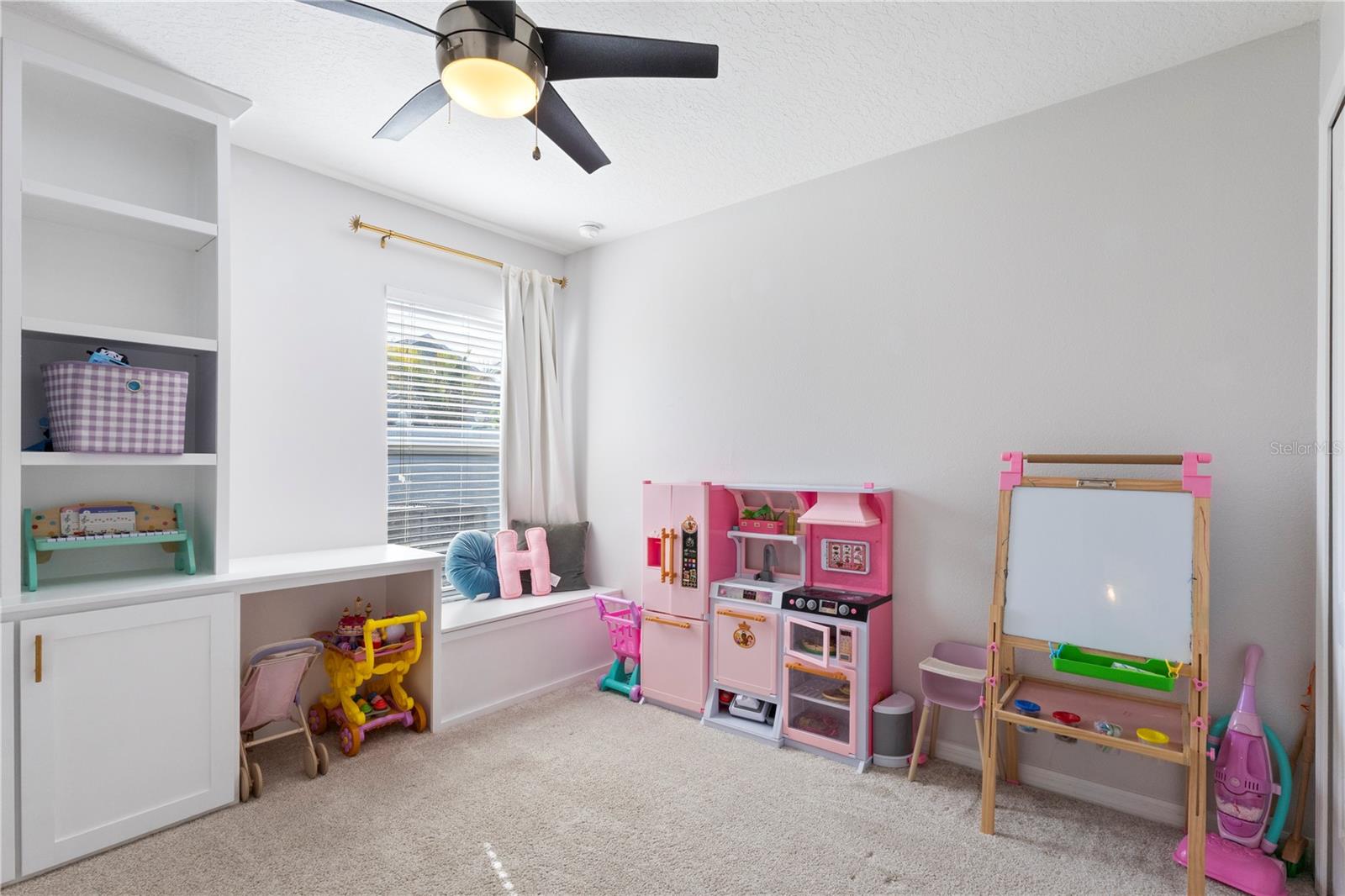 Built-in white shelving and window seat, plus abundant storage under a stylish ceiling fan.