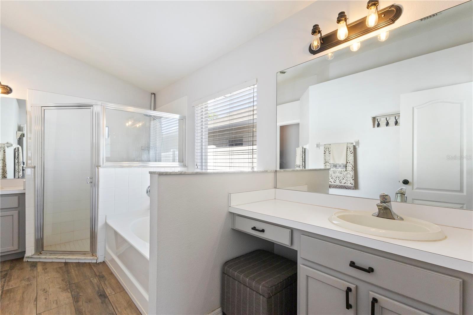 The light modern primary bathroom offers space for preparation or relaxtion with separate vanities!