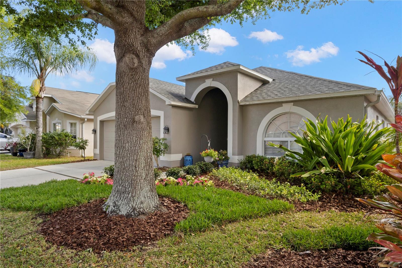 Stunning curb appeal showcasing this single-story home with a welcoming arched entry, manicured landscaping, mature shade tree, and vibrant flower beds! This home is waiting for you to call it yours!