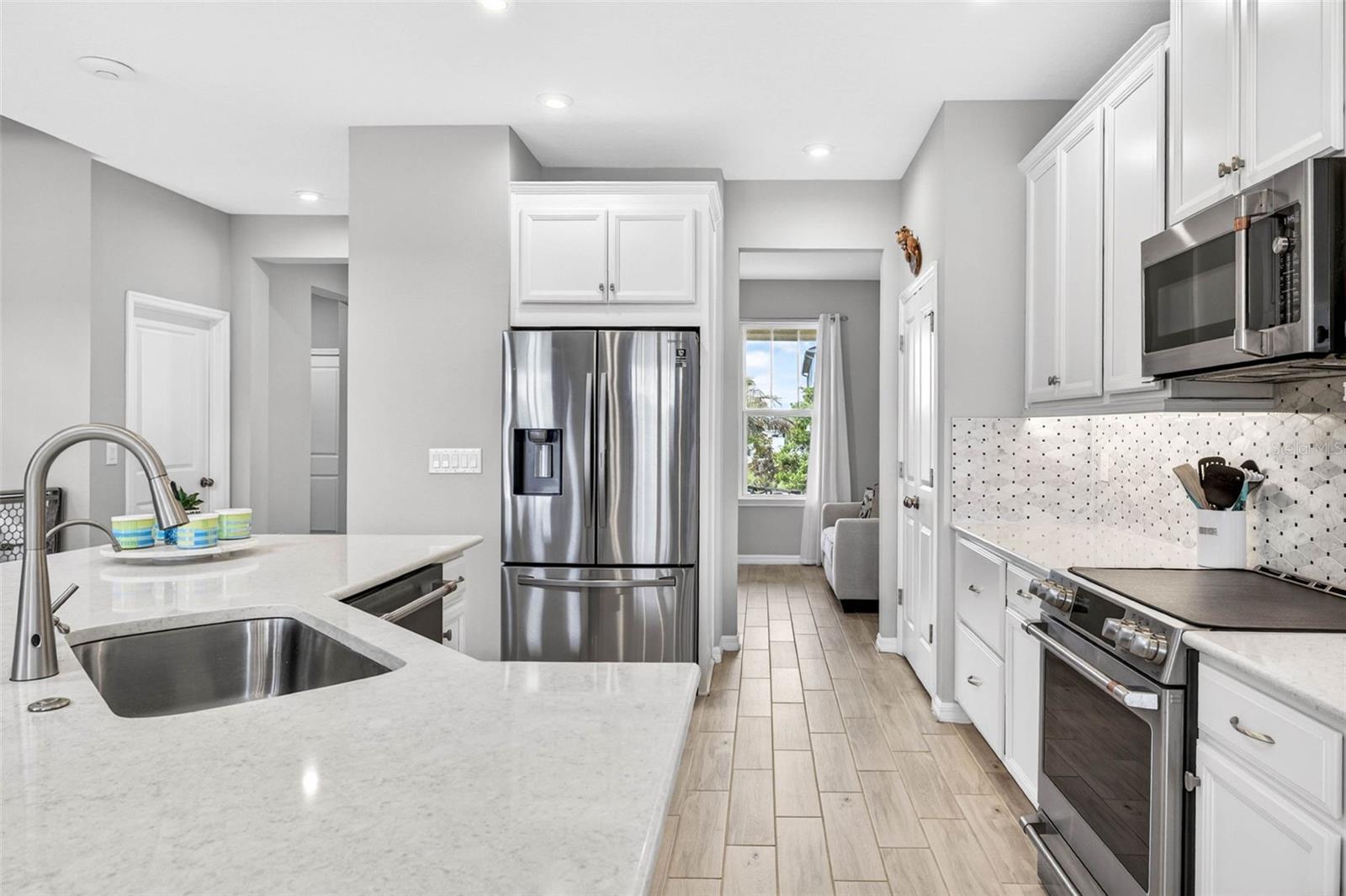 Bright and white kitchen with quartz countertops, stainless steel appliances, and bright lighting.