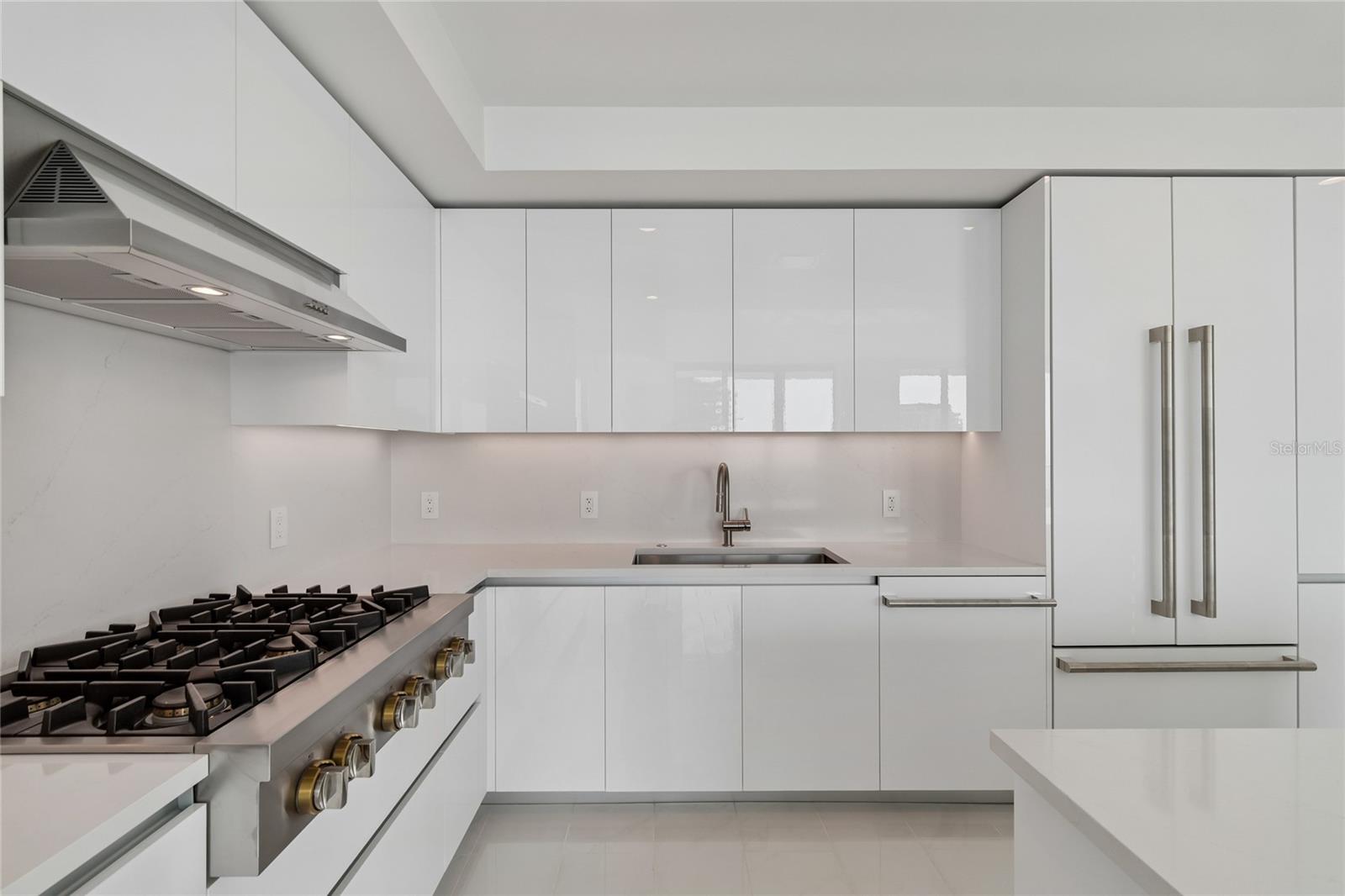 Custom High Gloss Cabinets with full quartz back splash and under cabinet lighting
