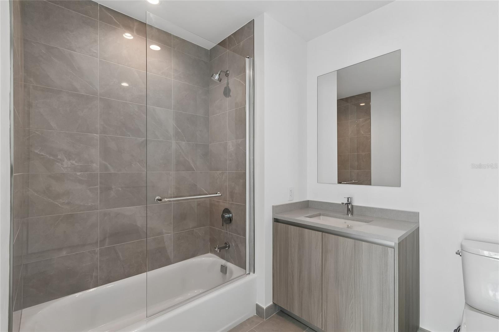 Guest suite shower has custom glass shower door designed for easy access