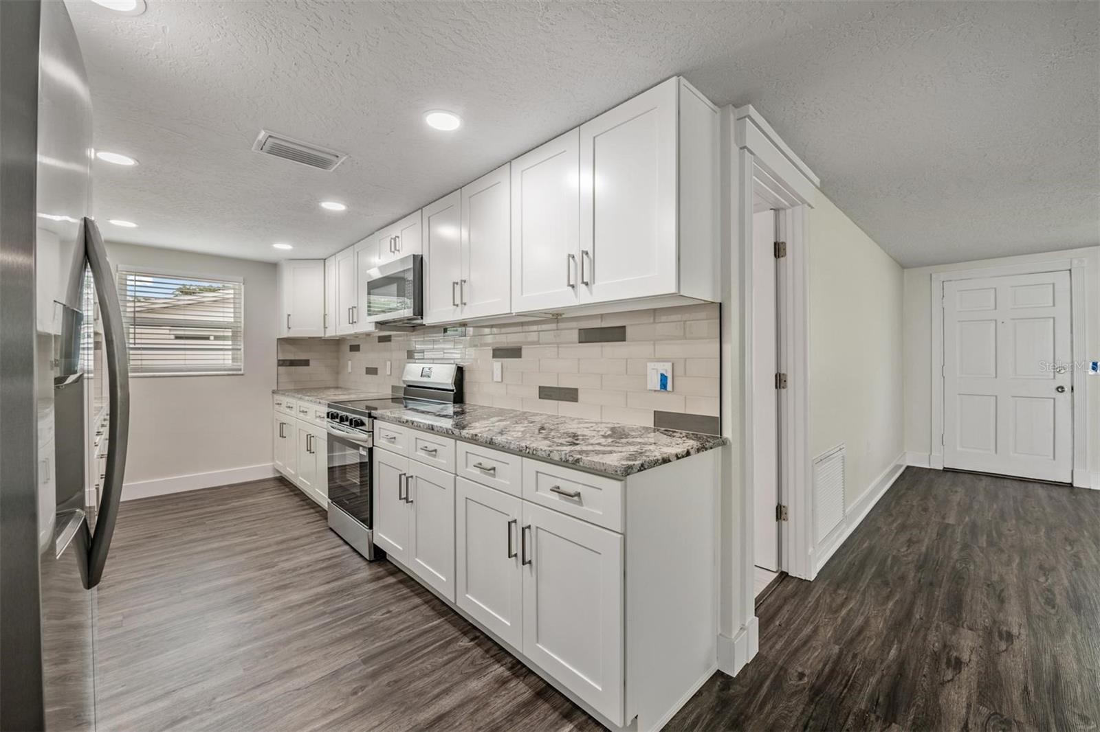 Luxurious kitchen.  All new appliances, granite countertops, shaker cabinets, hardware, flooring, can lights.