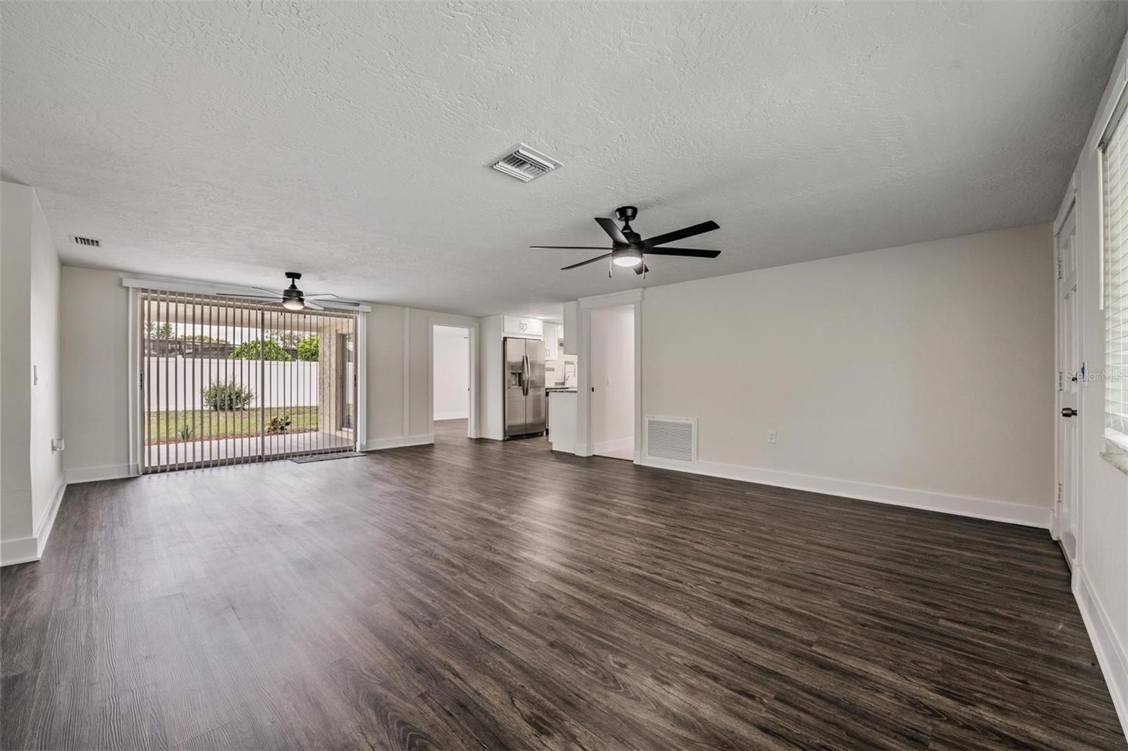 Front door to the Left.  Living and Dining area with sliders to the patio.  Door to right of kitchen is the laundry room, 2nd bathroom and garage.  Door to the left of kitchen is a primary bedroom with sliders to the patio.