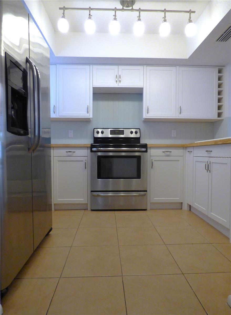 The updated kitchen features timeless white shaker cabinets and stainless steel appliances