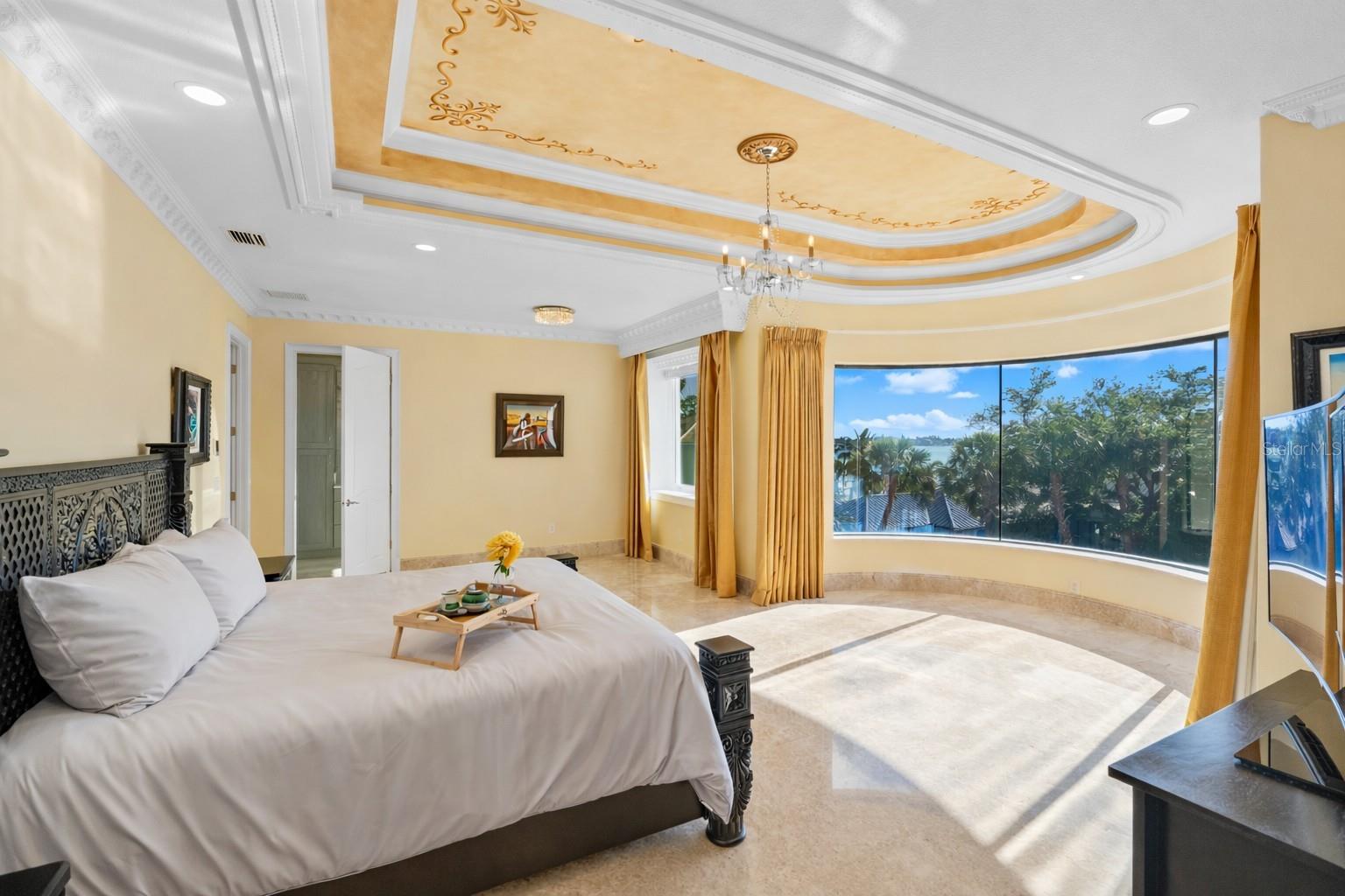 Bedroom 2 on the third level features a curved floor-to-ceiling window with endless views of the grounds and water.