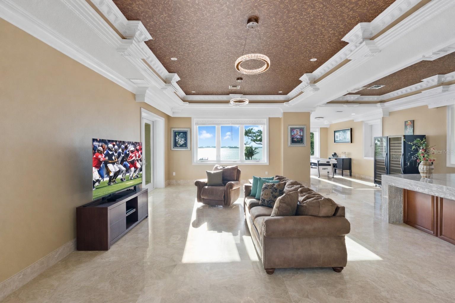 A statement space defined by dual coffered ceilings, offering endless possibilities for a game or entertainment lounge.