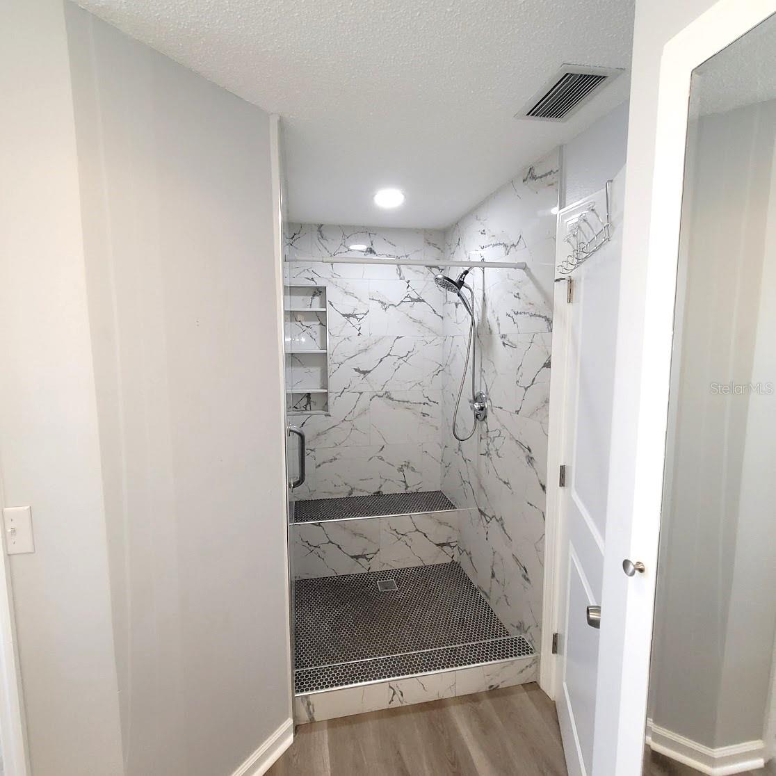 Gorgeous, oversized shower for Primary bedroom has a bench and shelves for soaps/ shampoos etc.