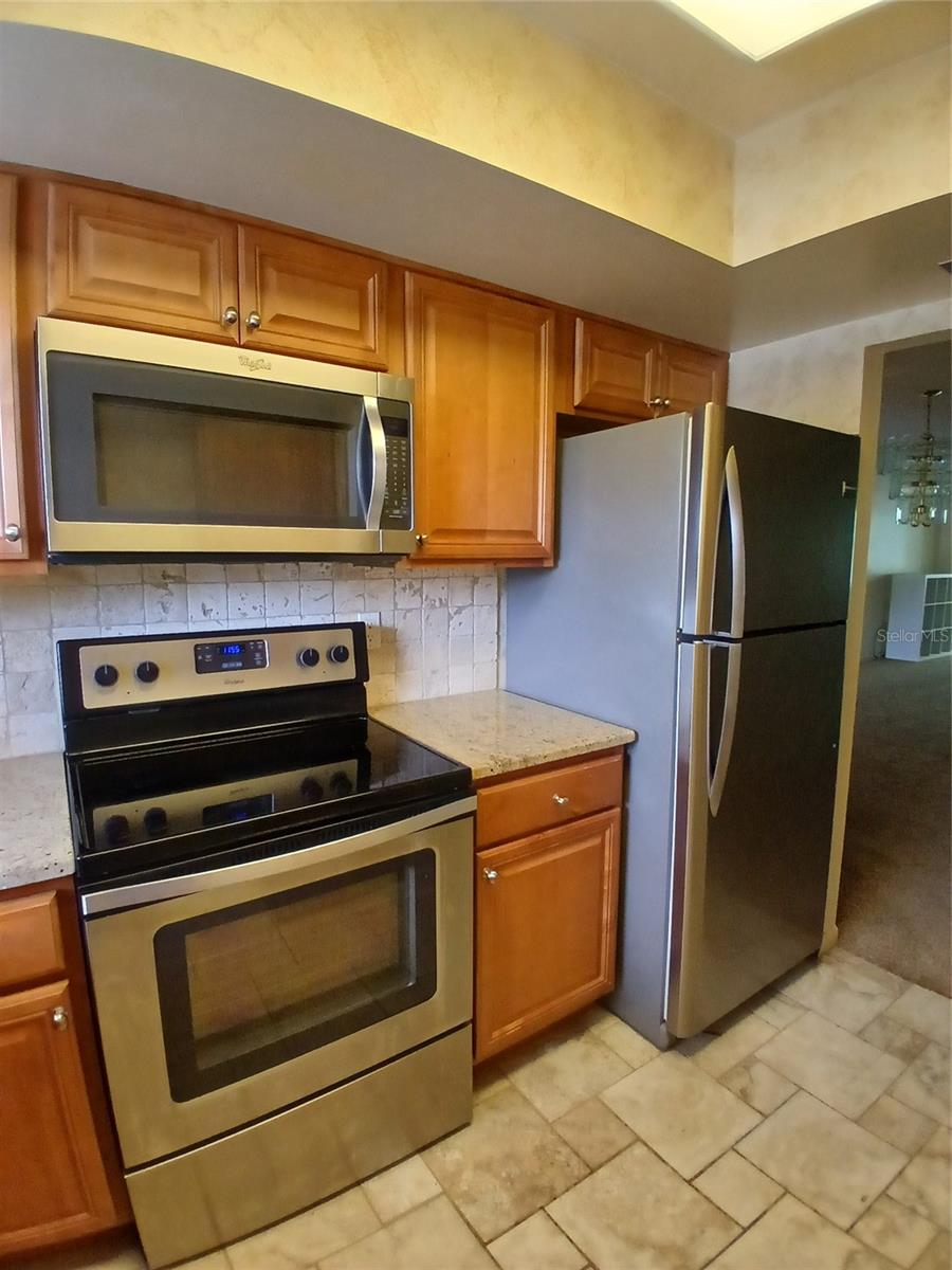 Full view of stove, microwave and the Frigidaire and the adjoining cabinetry.