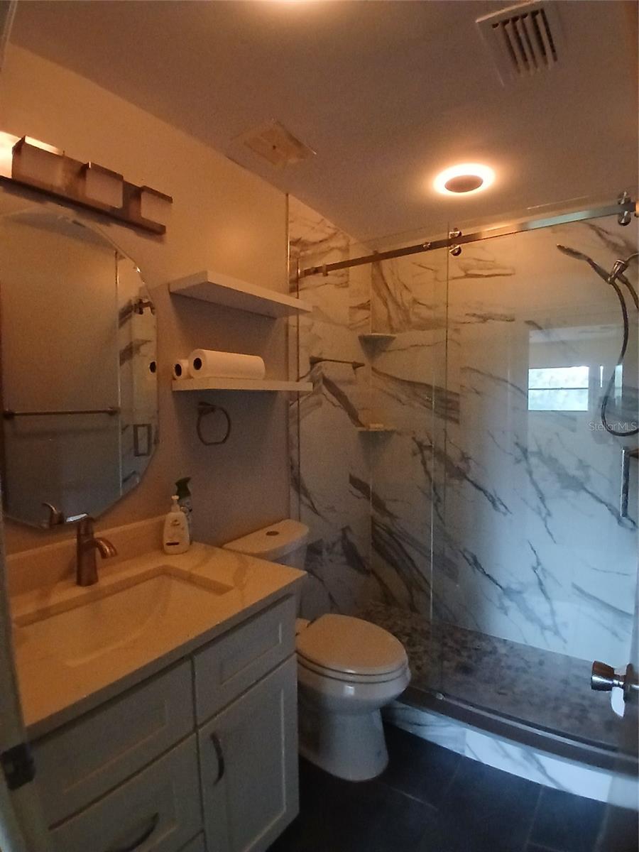 Bathroom showing the nice mirror over the vanity, the shelves over the toilet.