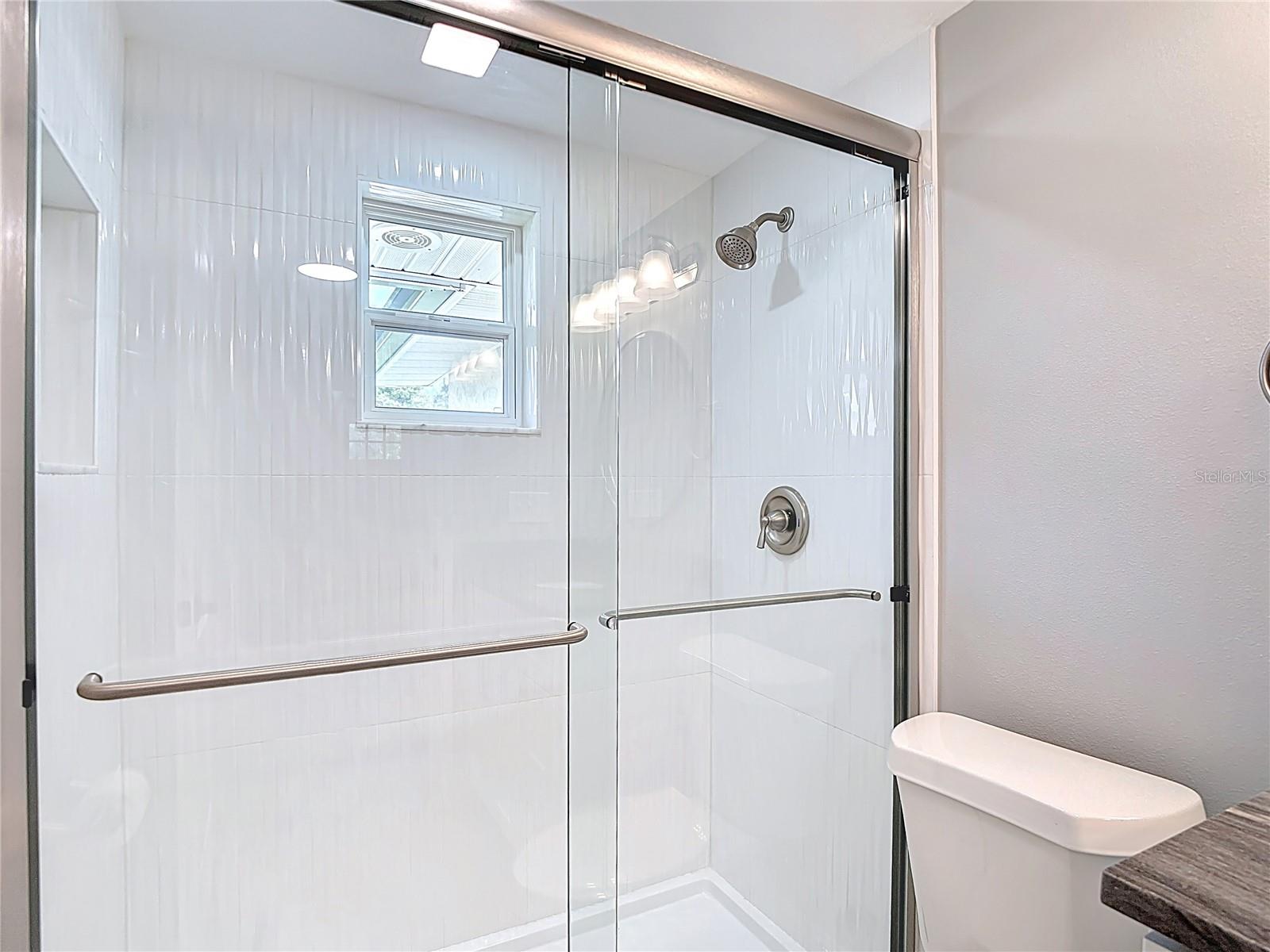 Wavy Tile shower stall with brushed nickel fixtures! Plenty of Light Too!