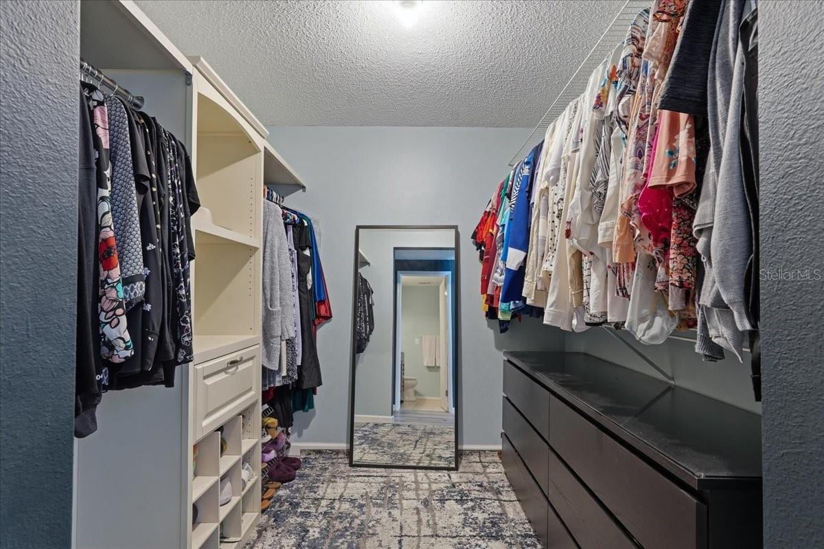 WALK IN CLOSET WITH CUSTOM BUILT ORGANIZING SYSTEM IN THE PRIMARY SUITE