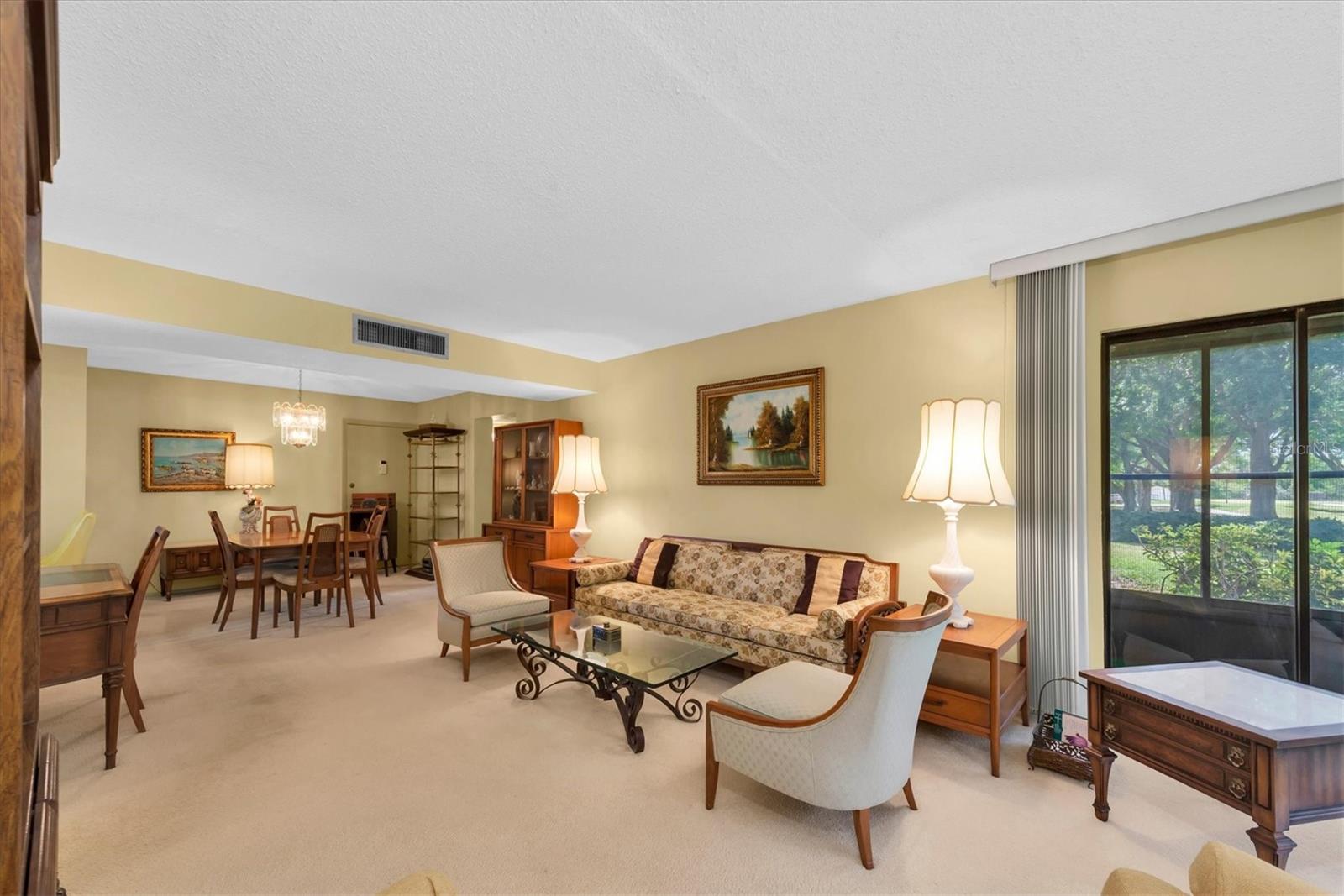 Living Room with a partial view of the outside area (Golf Course) and to the side is the Dining Room