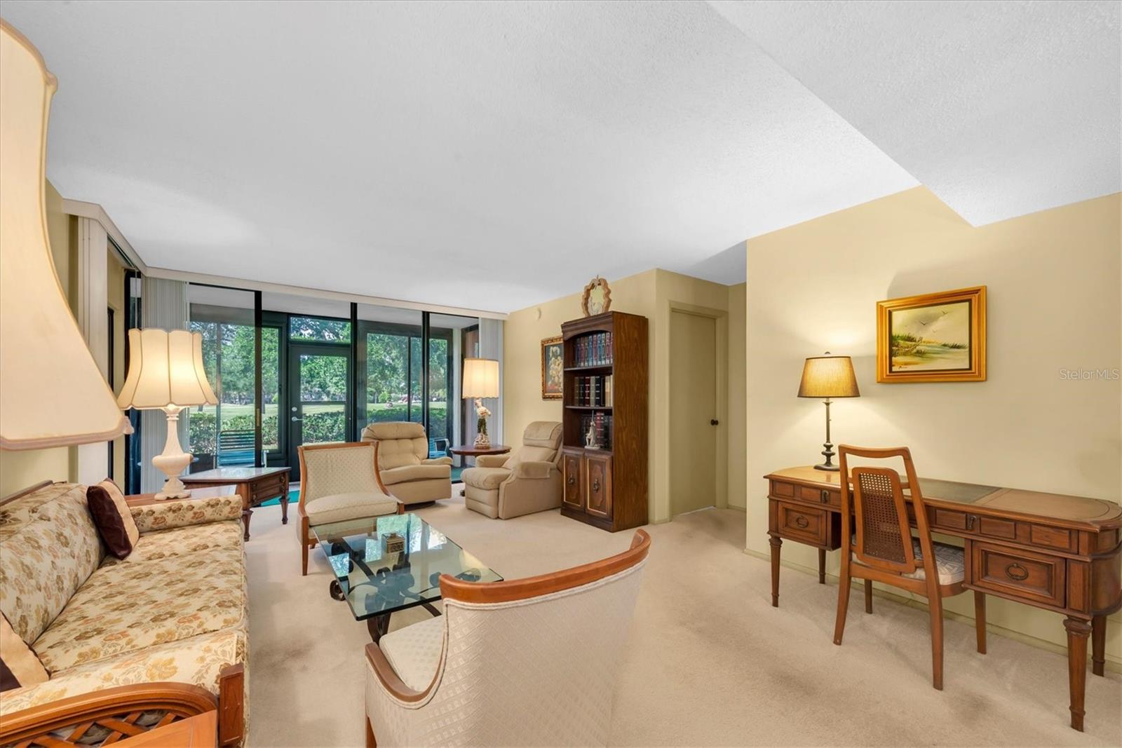 Living Room with a view to outside (Golf Course) and hallway at the rigtht leads to the Primary Bedroom