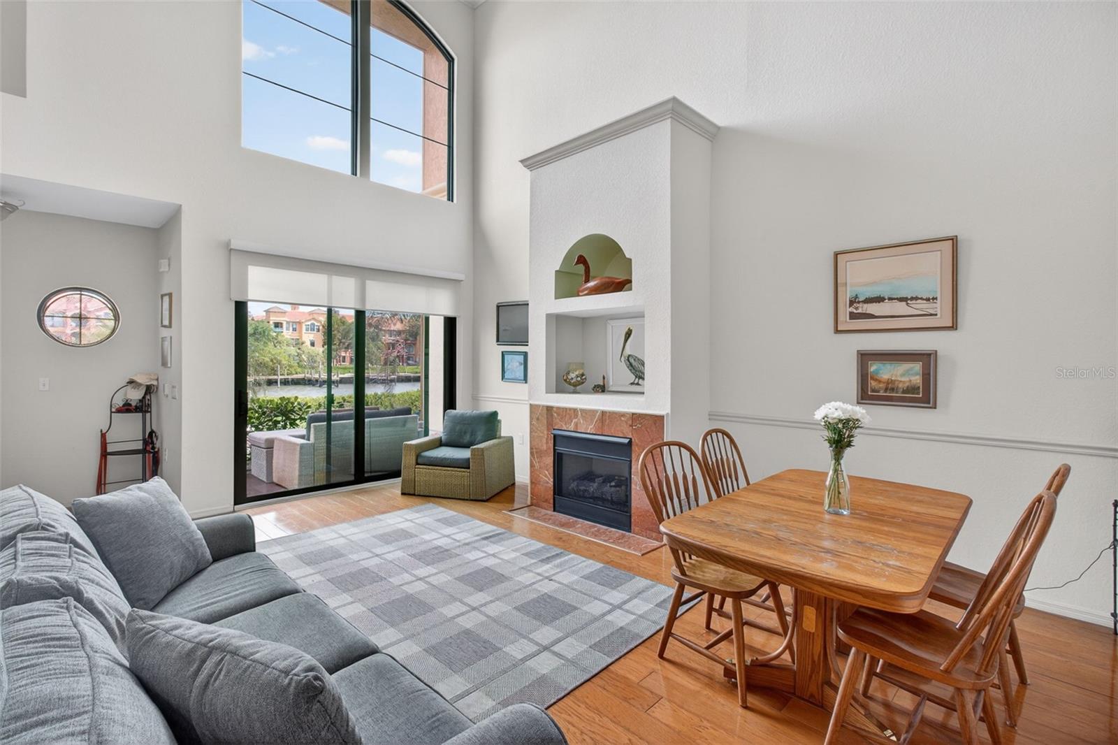 Two-story living room with fireplace, outdoor patio, and water views