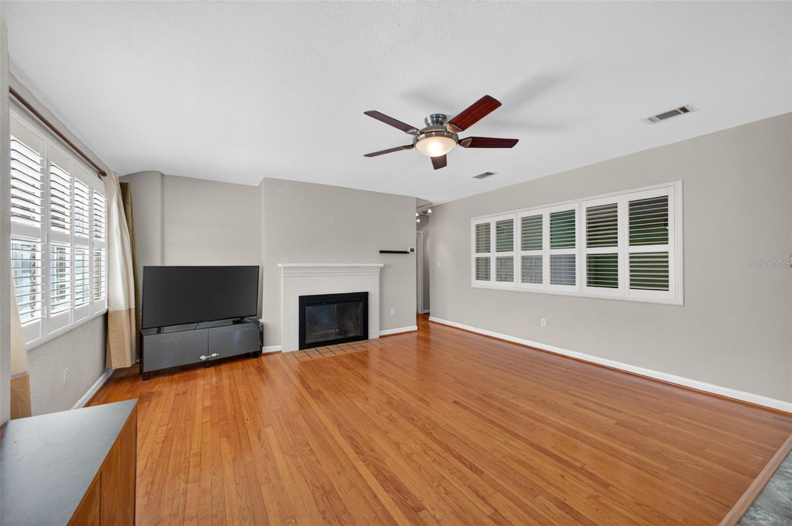 Large open living area with wood floors, wood burning fireplace that is warm and inviting