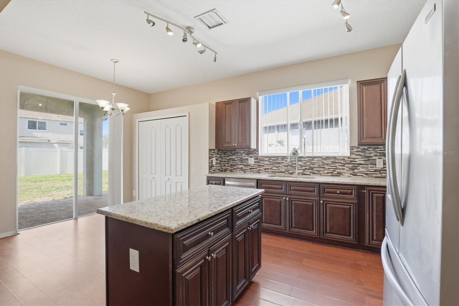 Open Kitchen with Granite Countertops, Center Island, Tile Backsplash, and Stainless Steel Appliances