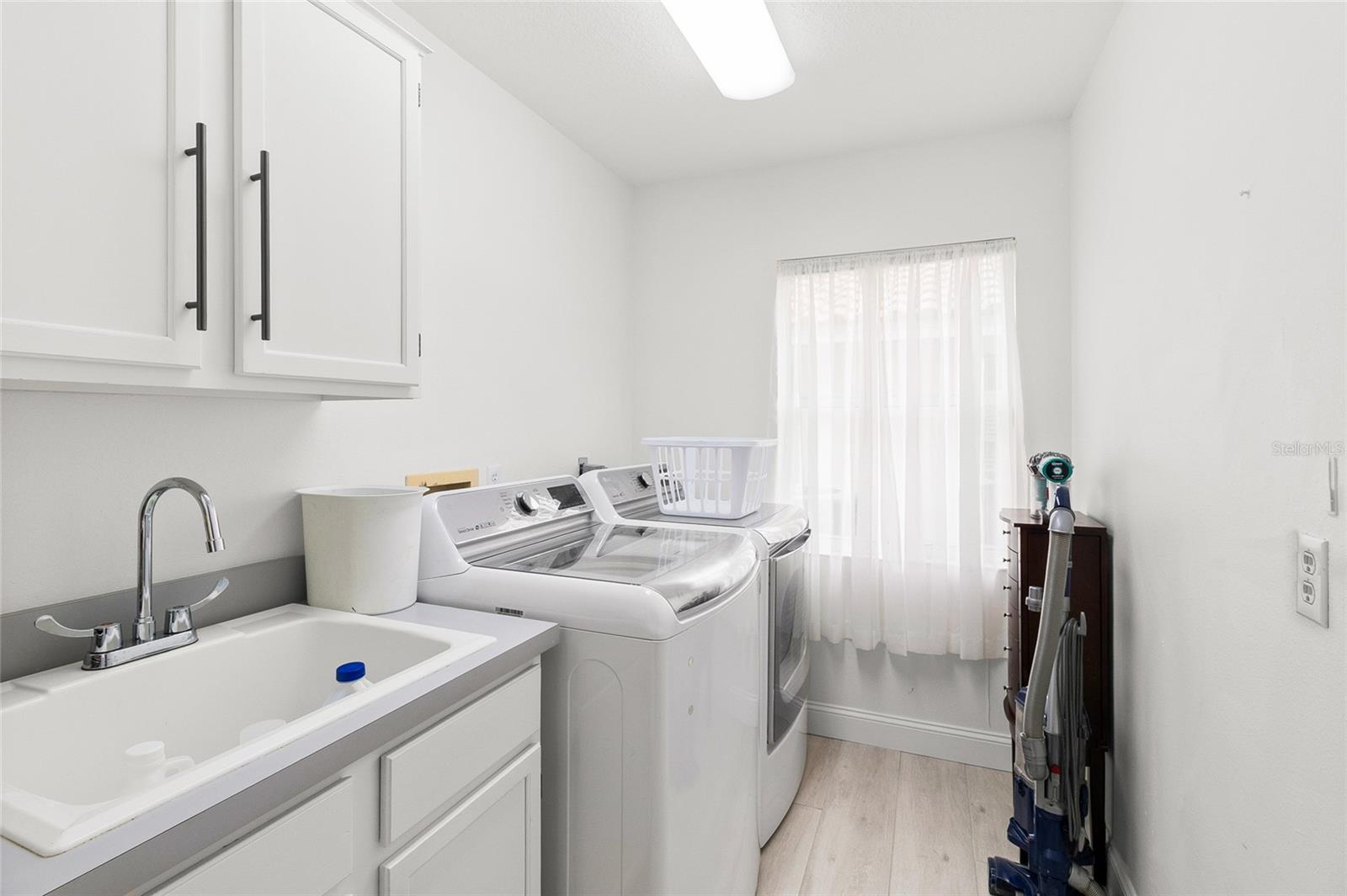 Inside laundry room with full size sink and lots of storage.