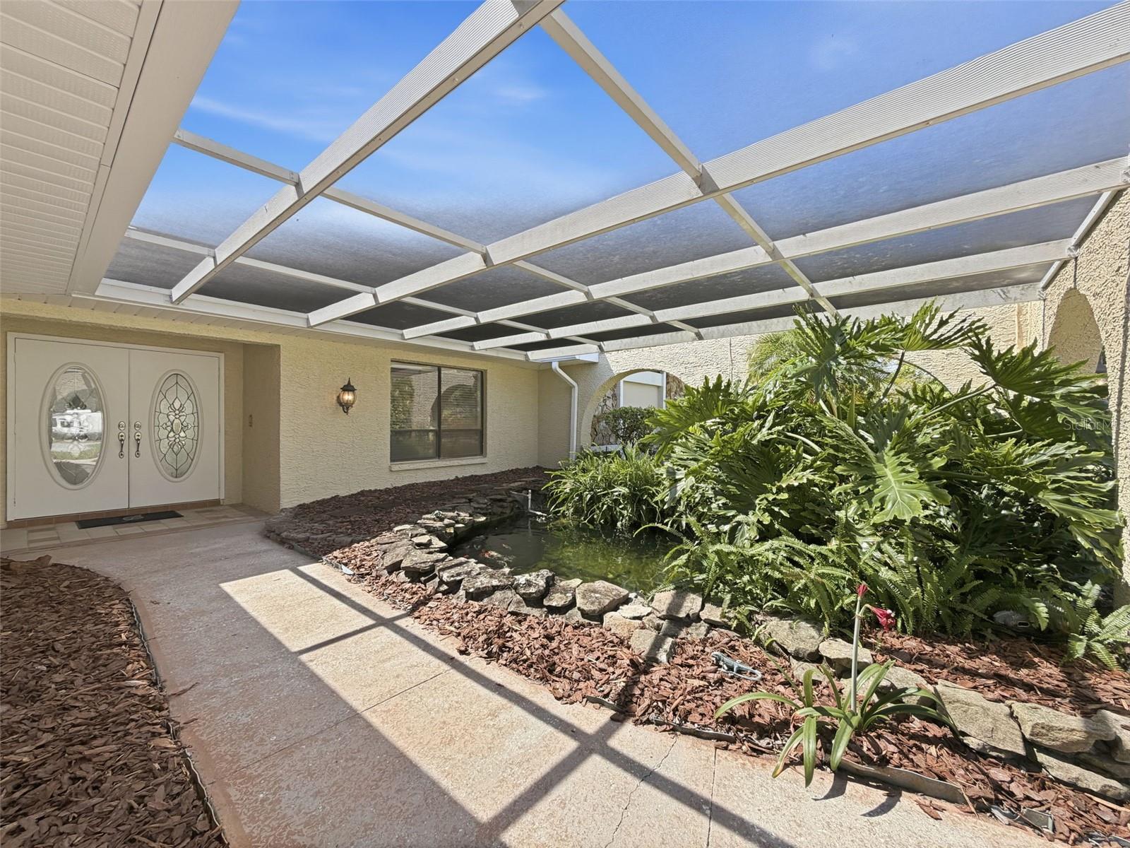 Beautiful tropical entry leads to the double front doors