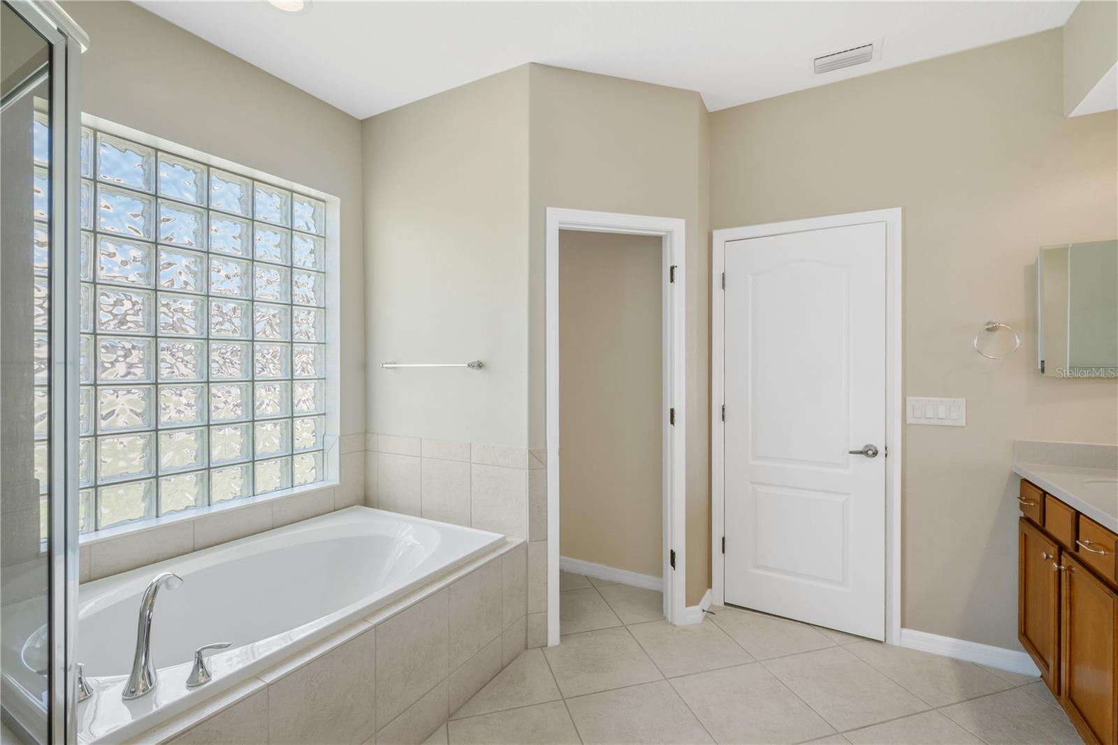 The primary bathroom features a private water closet and glass block windows that provide natural light while maintaining privacy.