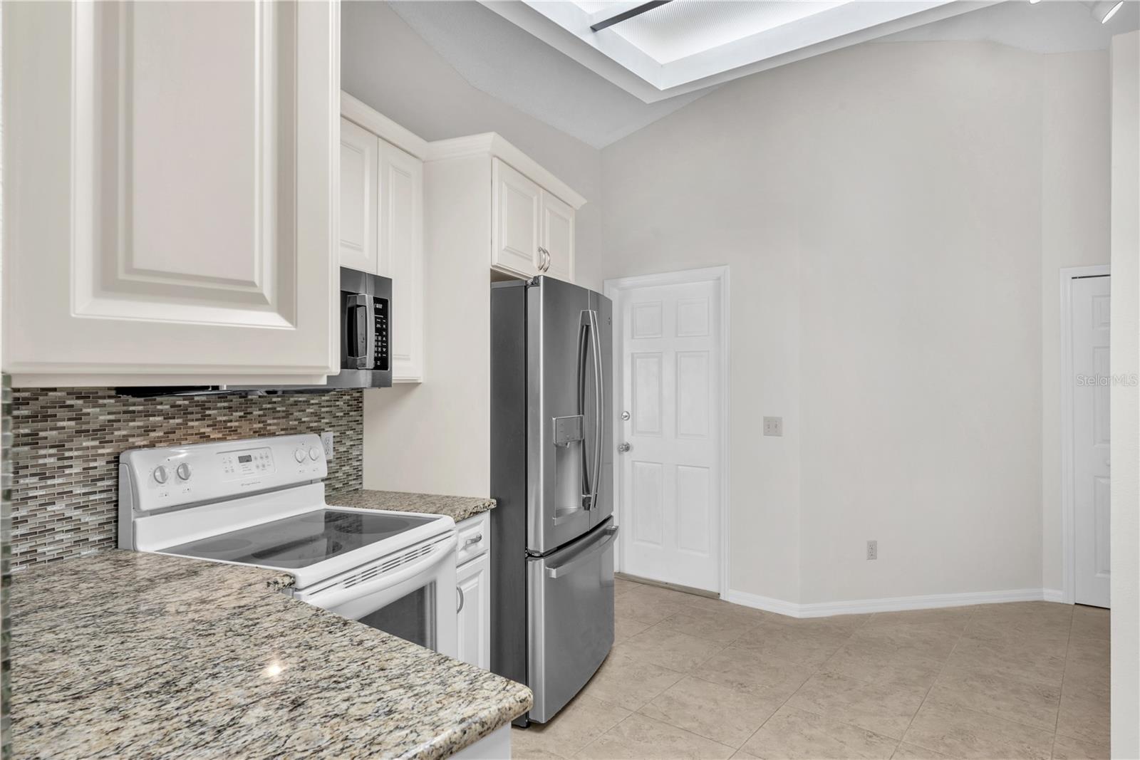 Updated kitchen, featuring granite countertops and a sea glass tile backsplash