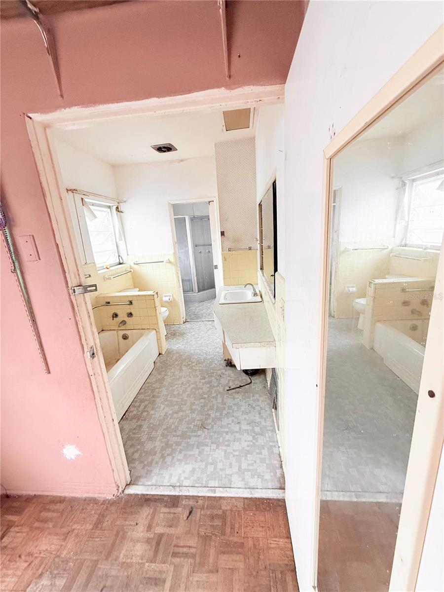 Large dual-access bathroom layout featuring original mid-century tile, extended vanity area, and separate shower space offering strong renovation potential.